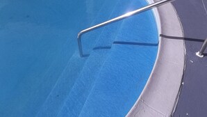 Una piscina con una escalera metálica para entrar.
