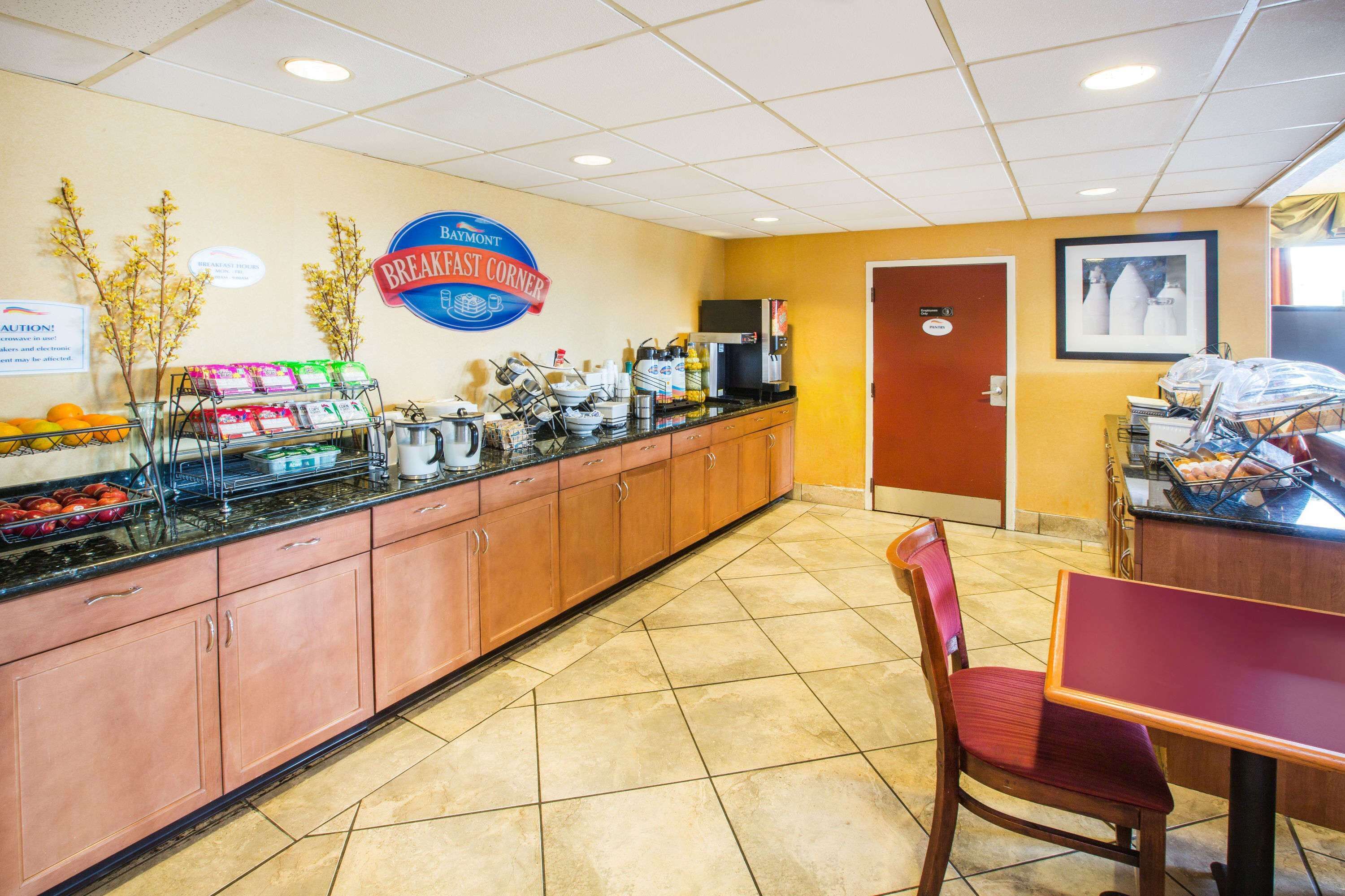 A breakfast area with a counter, coffee machines, and a sign for 'BAYMONT BREAKFAST CORNER'.