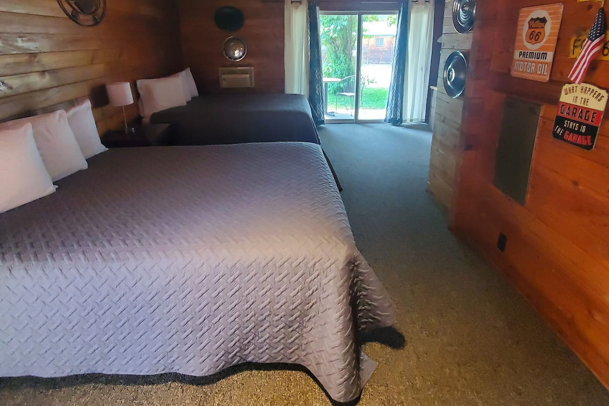 Una habitación de cabaña acogedora con una cama grande, una mesita pequeña y un ventanal con cortinas.