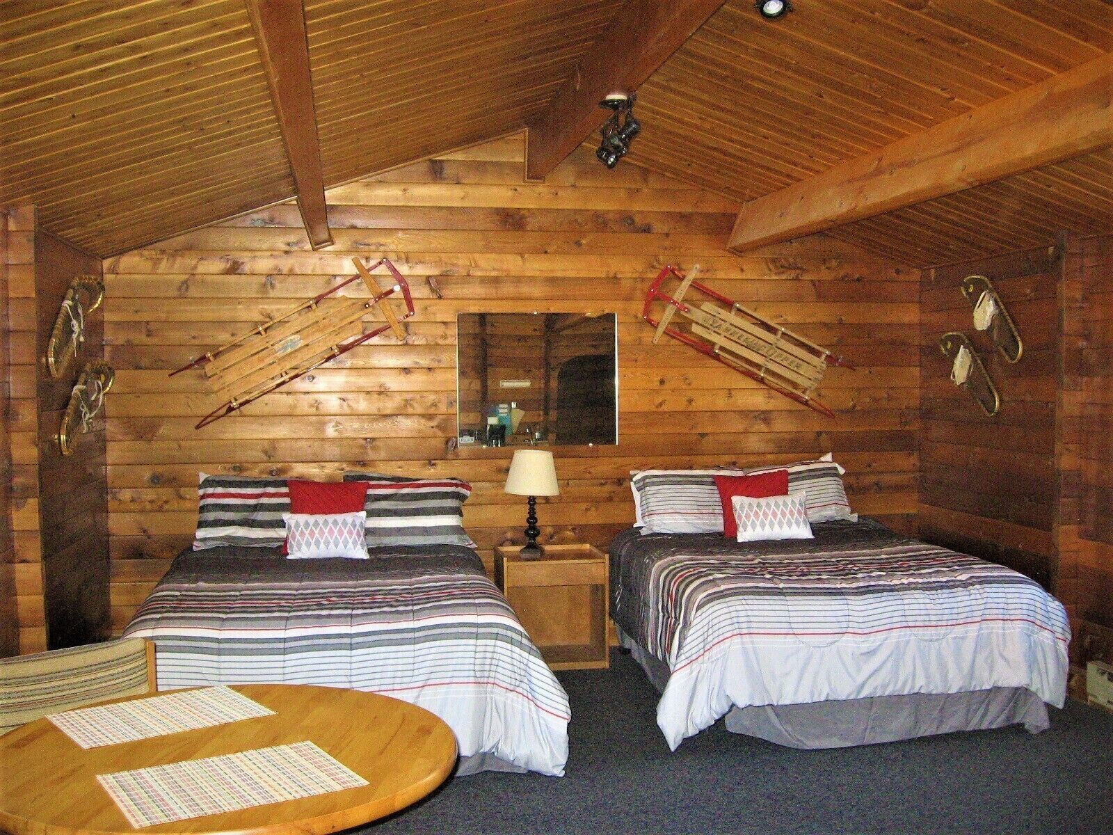 Una habitación de cabaña acogedora con dos camas, techo de madera y una pequeña mesa con papeles.