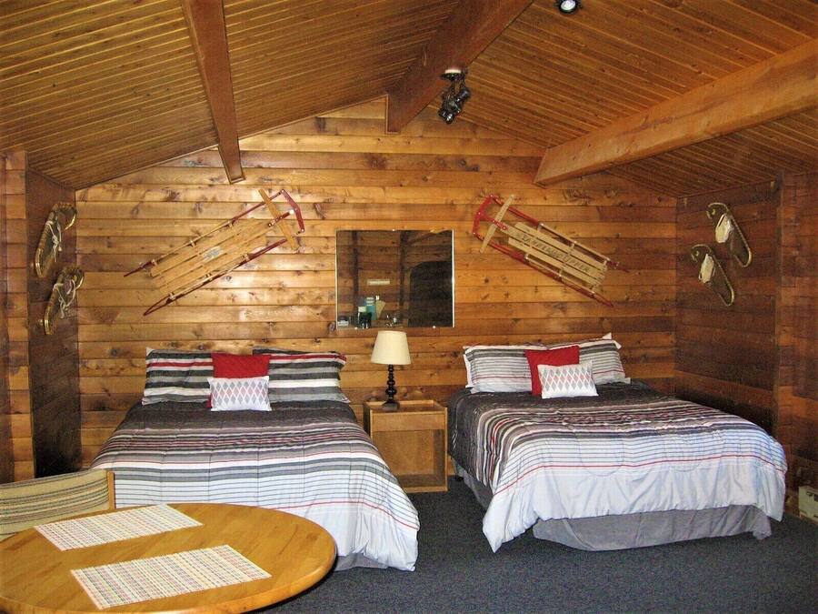 Um quarto de cabana acolhedor com duas camas, teto de madeira e uma pequena mesa com papéis.
