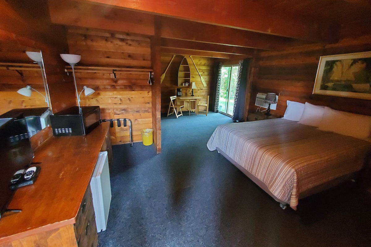 Una habitación de cabaña de madera con cama, escritorio y silla.