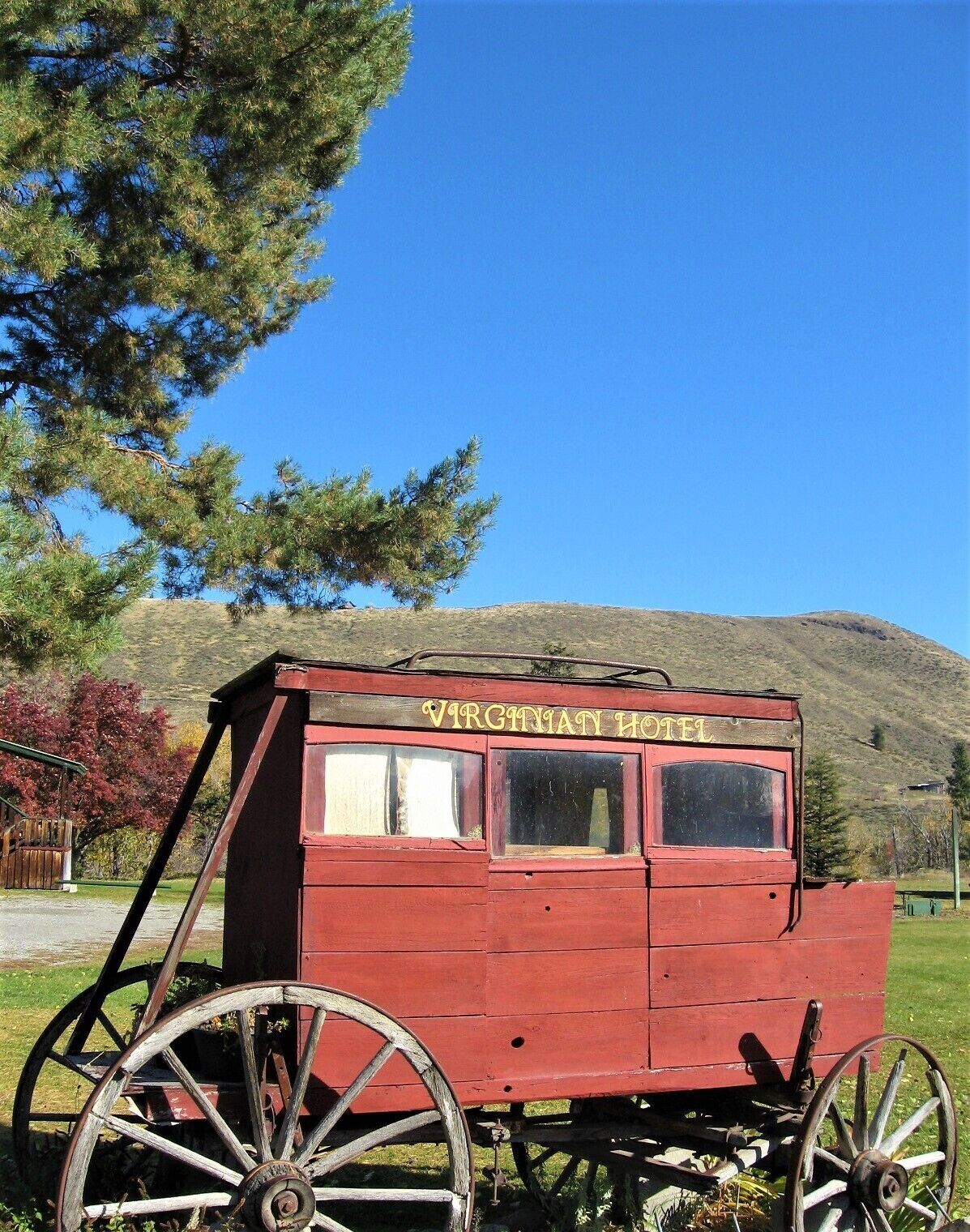 A red wooden carriage with the sign "VIRGINIATY HOTEL" on top, featuring large wooden wheels and a simple, rustic design.