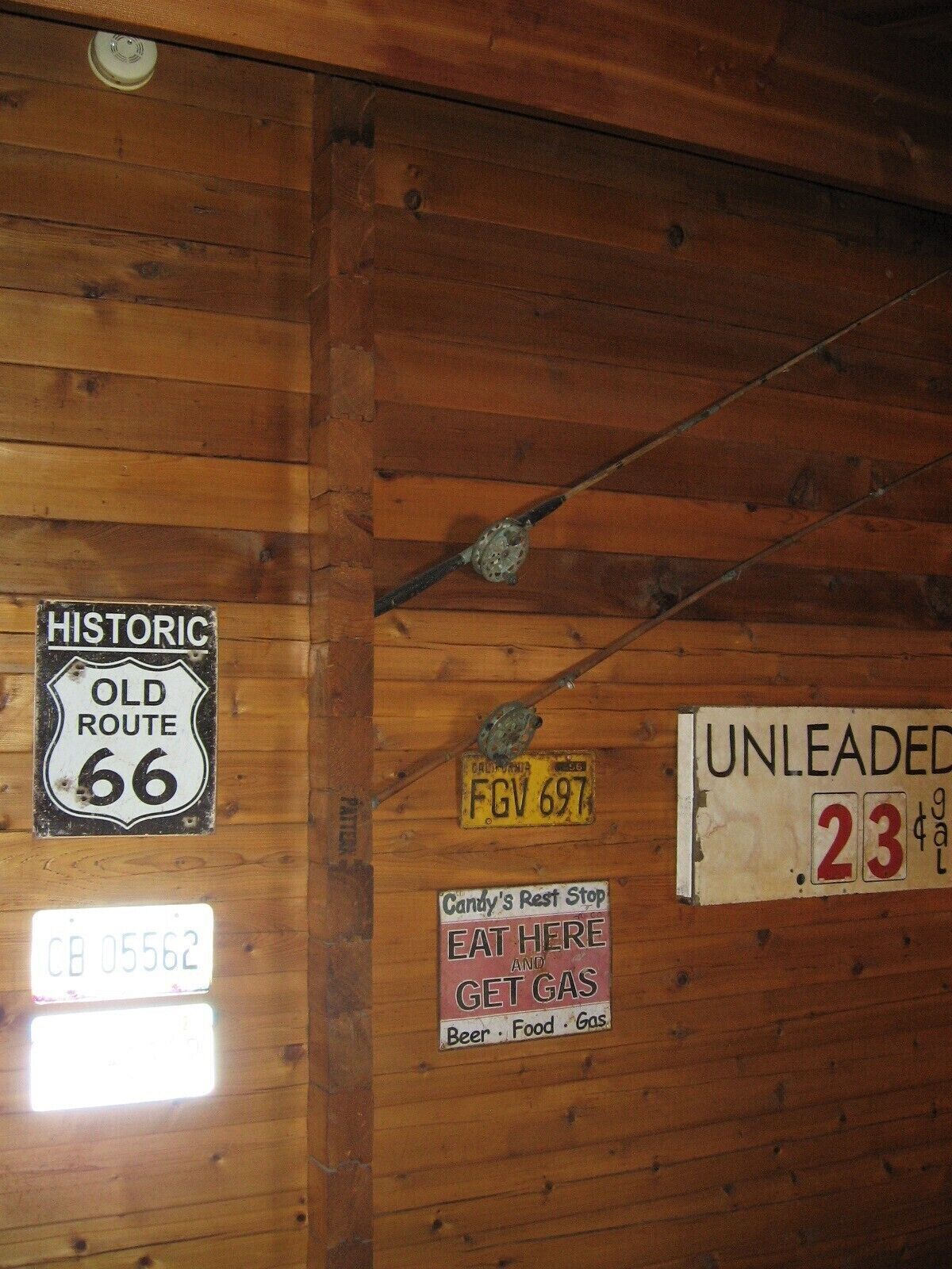 A wooden wall with various signs, including a historic route sign, a license plate, and a sign for Candy's Rest Stop.