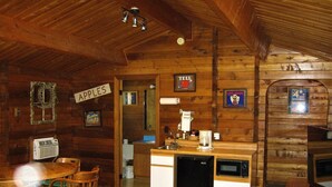 A cozy cabin interior with a wooden interior, a kitchen area with a refrigerator, microwave, and coffee maker, and a dining area with wooden chairs. - Virginian Resort (Winthrop)