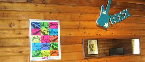 En trævæg med et indrammet plakat fra Des Moines Arts Festival 2004, et indrammet certifikat og et blåt guitarskilt med stjerner.