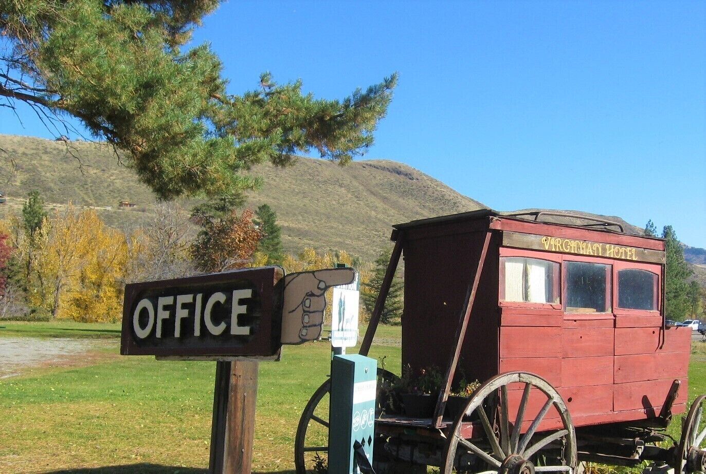 Ein alter, roter Wagen mit der Aufschrift 'VIRGINIA HOTEL', und ein Schild weist auf ein Büro in der Nähe hin.