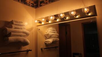 A bathroom with a mirror, towel rack, and a wall-mounted light fixture.