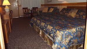 Une chambre d’hôtel avec un grand lit, un bureau avec une lampe, une chaise, un canapé et une table à manger.