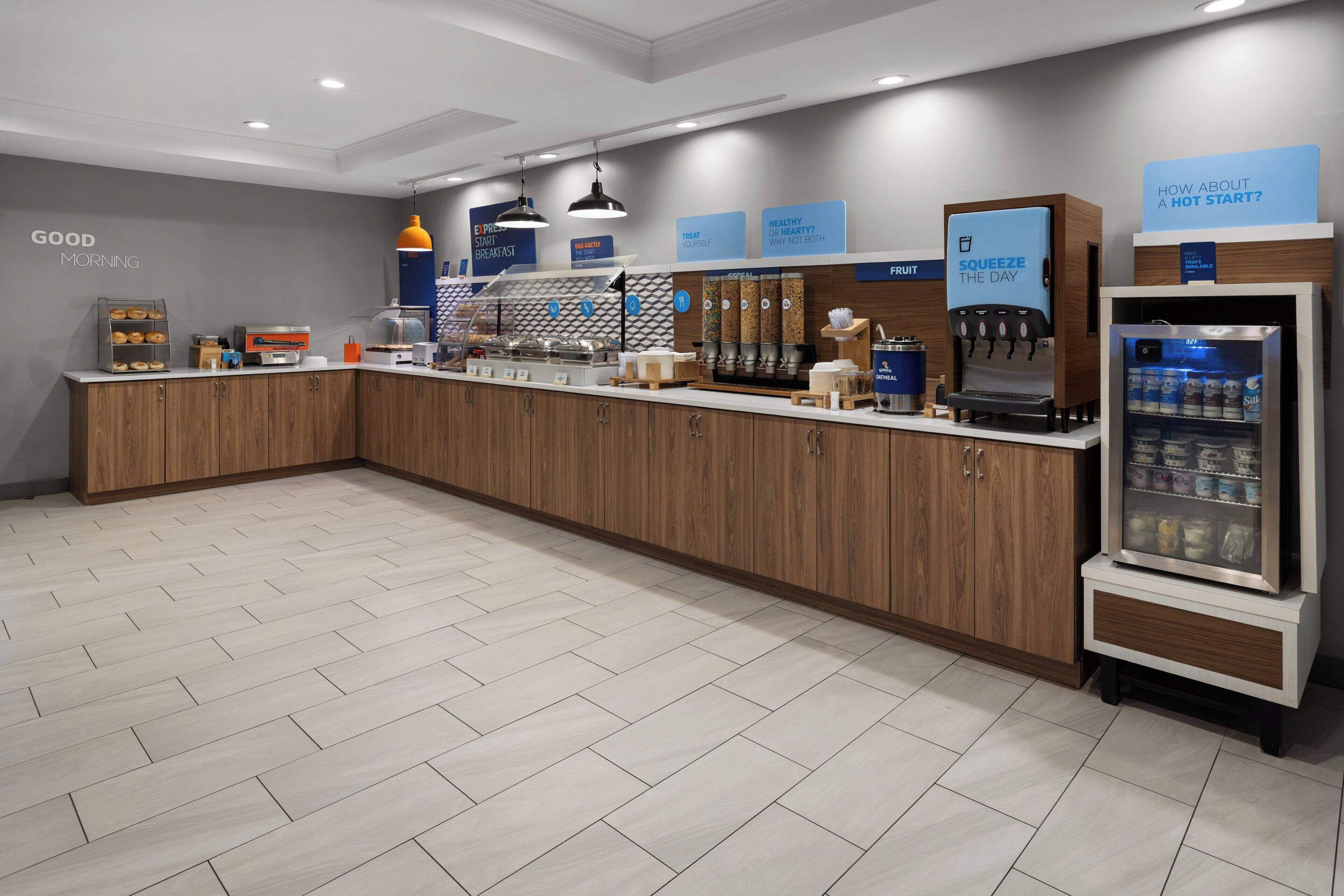 A modern breakfast area with a counter, coffee machines, and a refrigerator.
