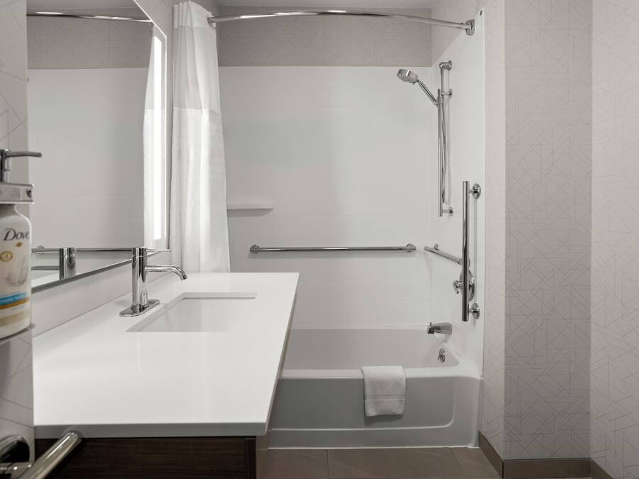 A modern bathroom with a bathtub, a shower, and a vanity with a sink.