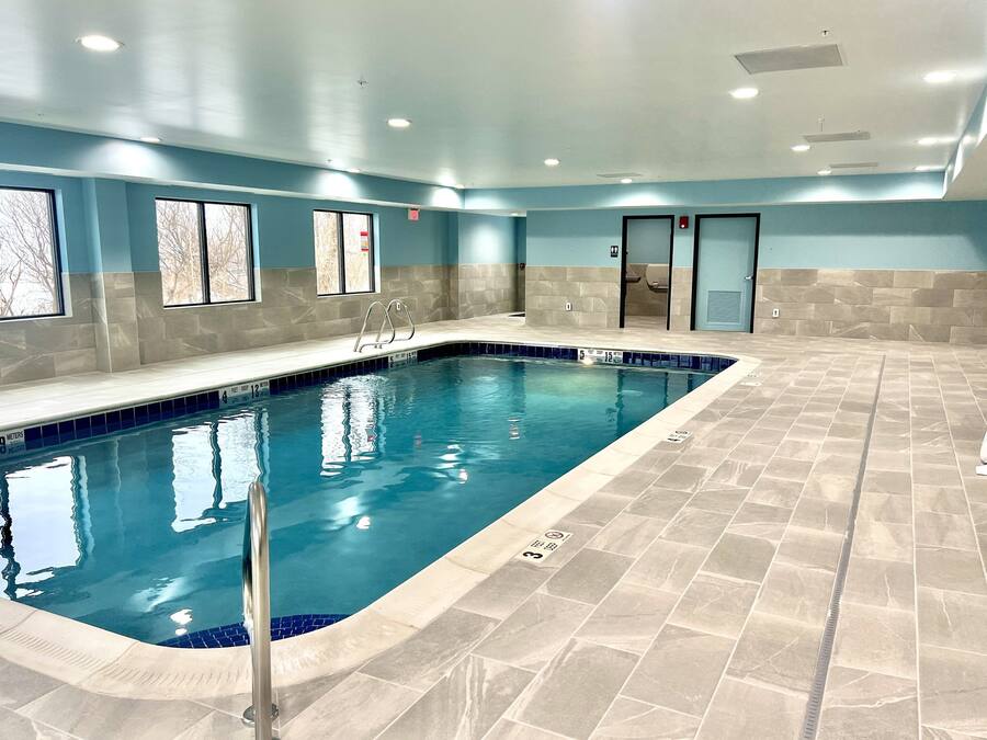 An indoor swimming pool with clear water, tiled walls, and a tiled floor.