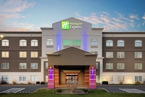 A Holiday Inn Express building with a prominent entrance, multiple windows, and a parking lot. - Holiday Inn Express Syracuse Fairgrounds by IHG (Syracuse)