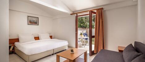 A hotel room with a bed, a sofa, a small table, and a view of the outside.