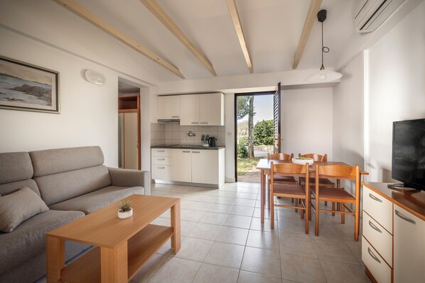 Un espai de viure modern amb sofà, taula de dinar i zona de cuina.