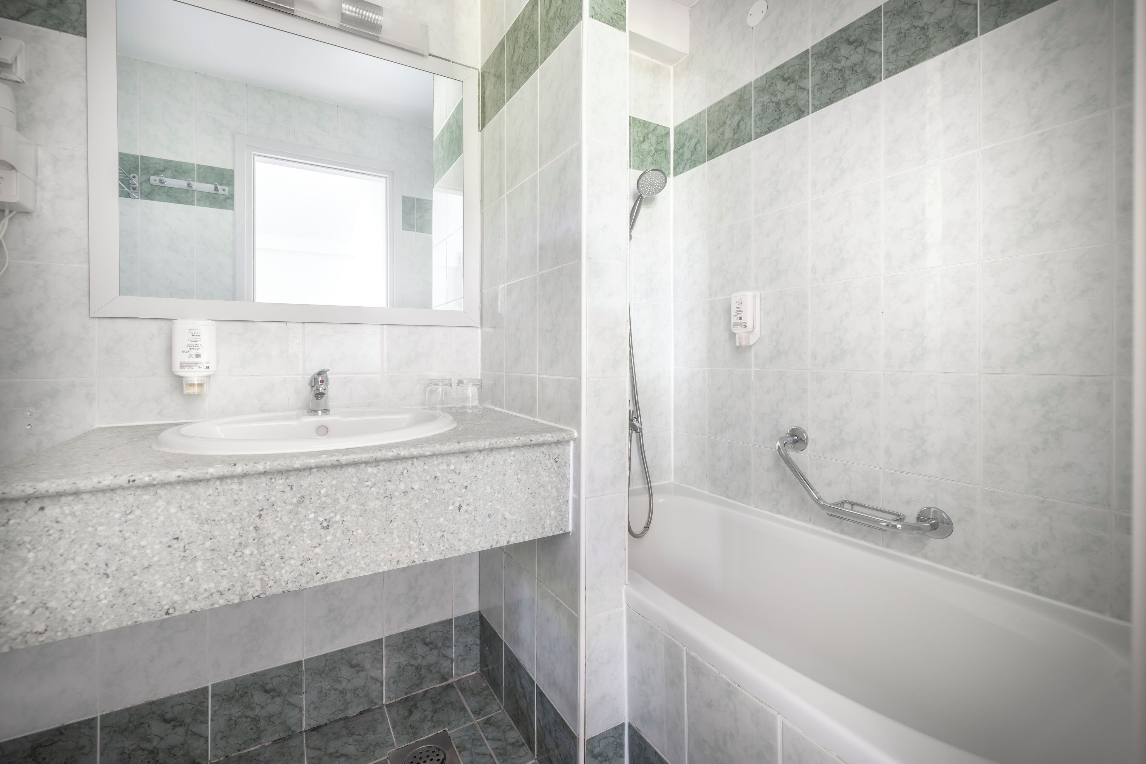 Un baño con lavabo, espejo y ducha.