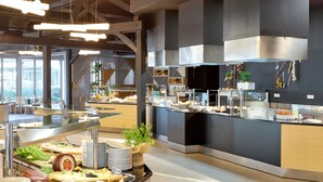 A buffet area with various food items and a modern kitchen in the background.