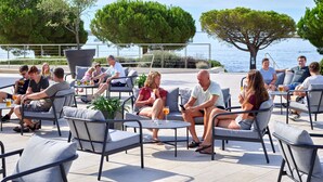 An outdoor seating area with multiple tables and chairs, overlooking a body of water.