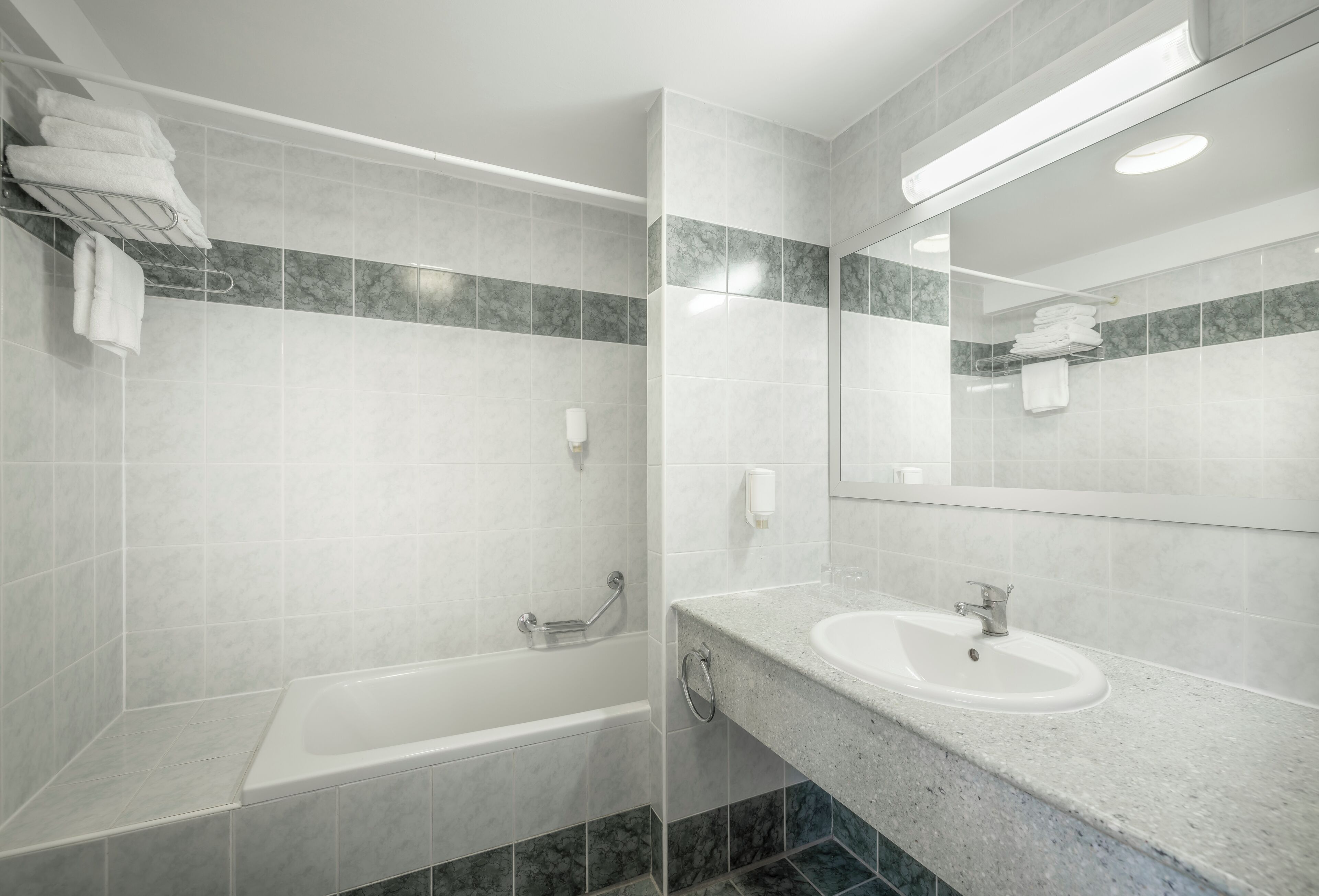 A modern bathroom with a bathtub, a sink, and a towel rack.