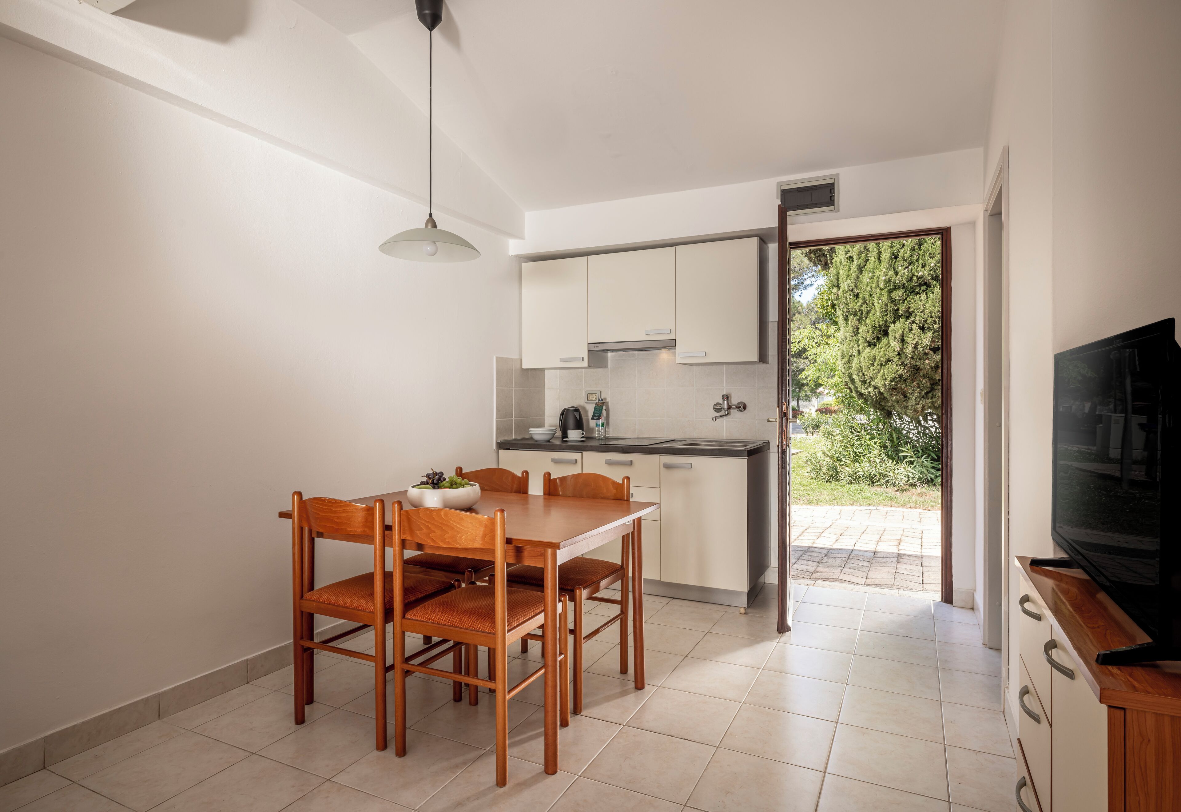 A compact kitchen with a dining area, a TV, and a view of the outdoors.