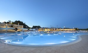 Relax by the pool surrounded by a modern architectural setting, complete with lounge chairs and umbrellas.