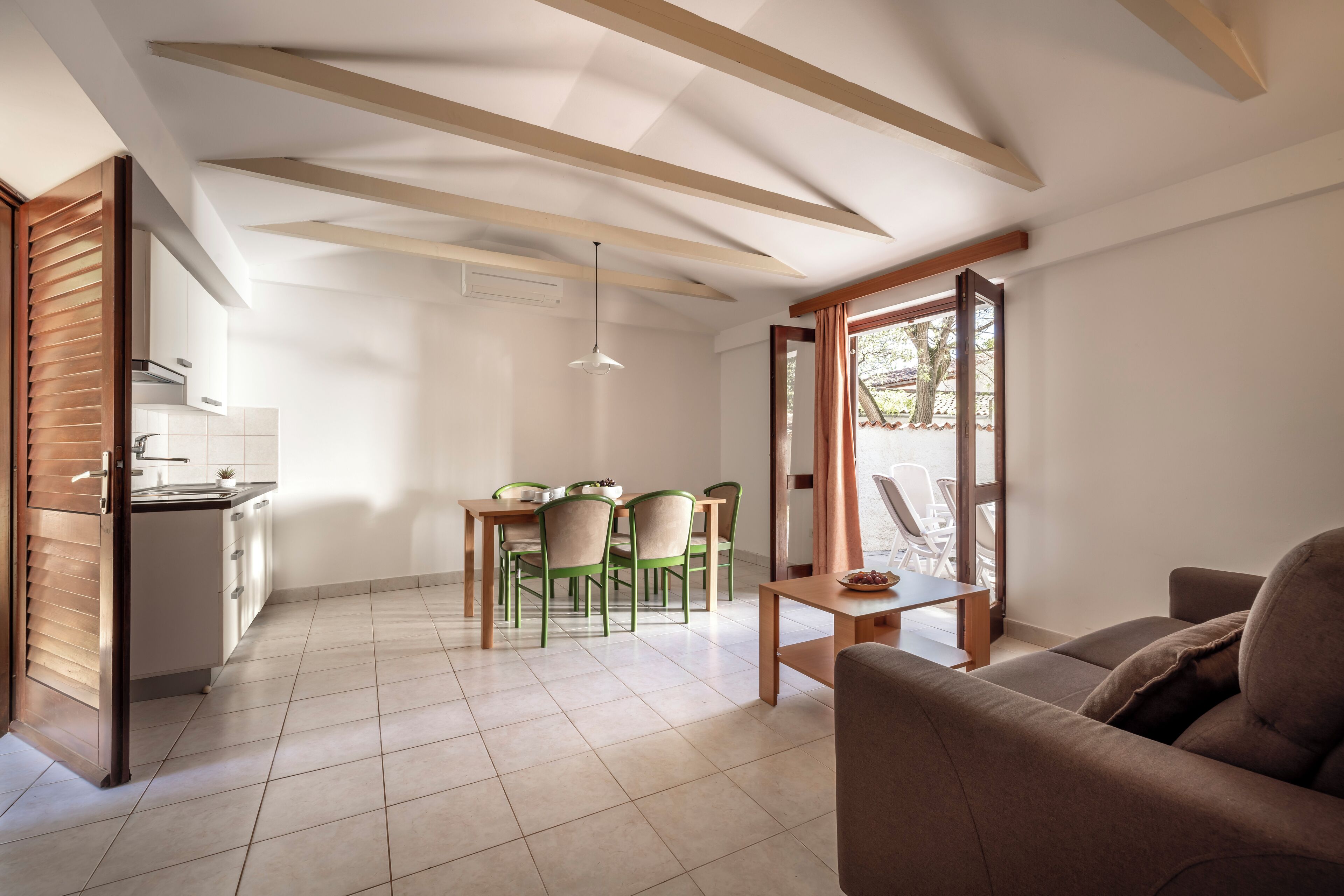 A modern kitchen with white cabinets and a dining area with green chairs.