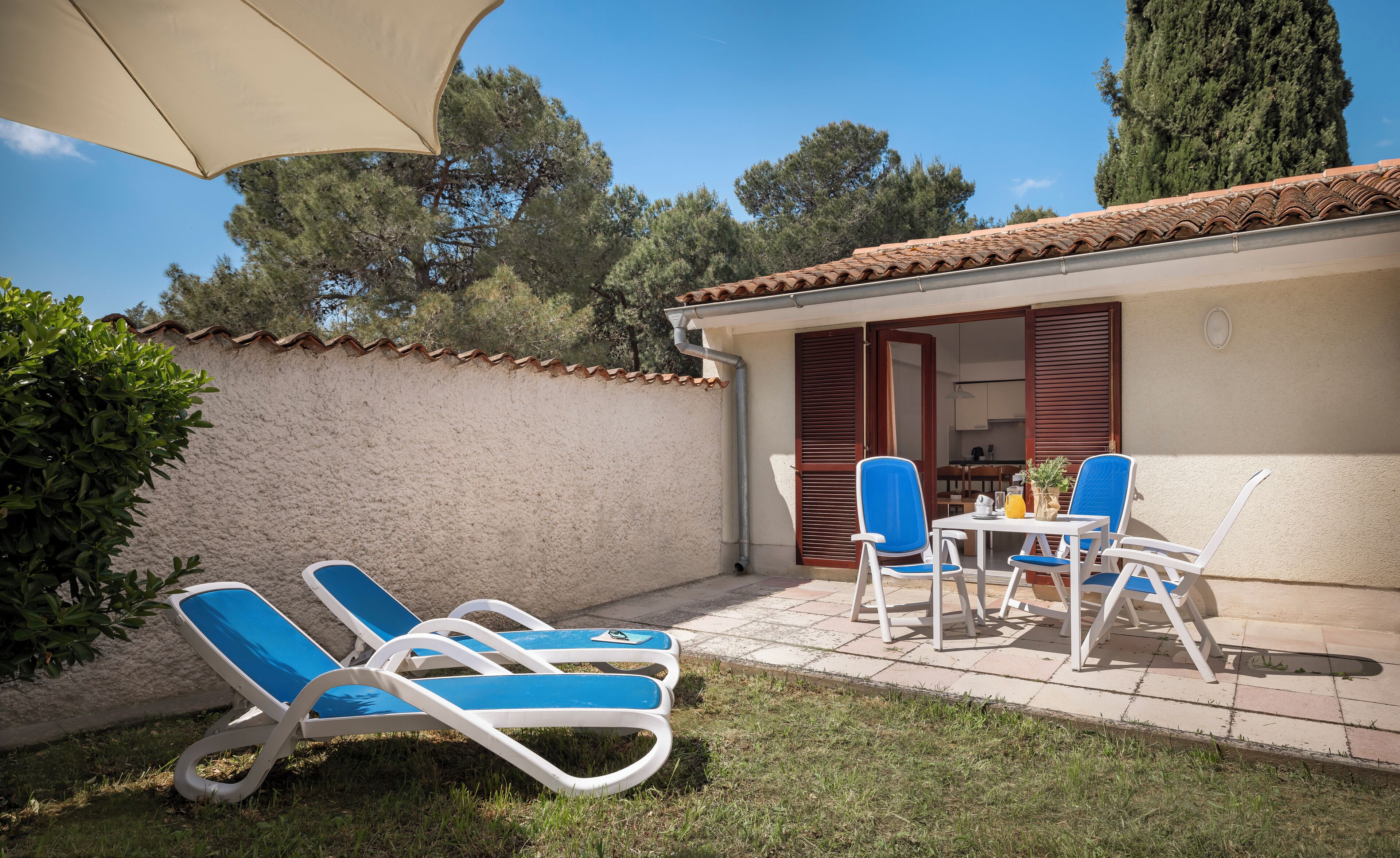 A patio with lounge chairs, a table, and a small kitchen area visible through an open door.