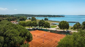 A tennis court with a view of a lake and hills in the background.