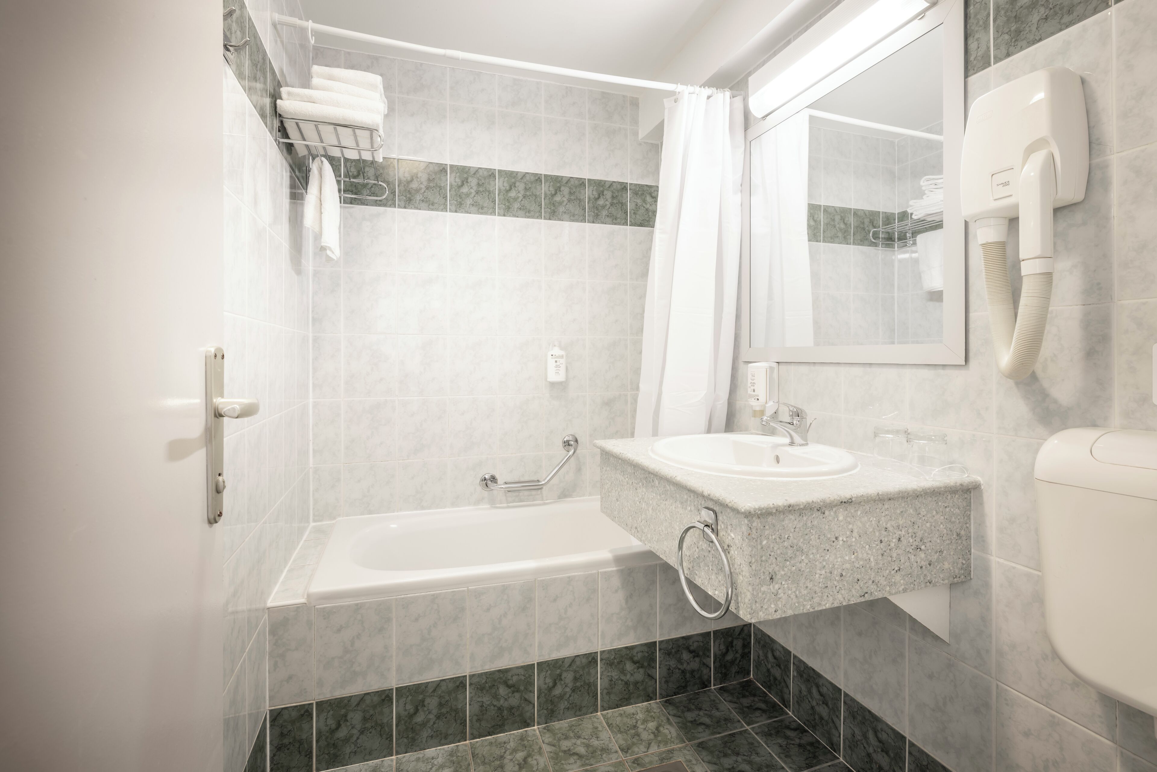 Une salle de bain équipée d’une baignoire, d’un lavabo, de toilettes et d’un porte-serviettes.