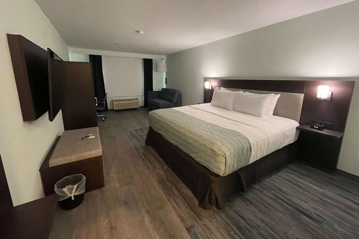 Une chambre d’hôtel avec un grand lit, des tables de chevet, un téléviseur fixé au mur et un bureau avec une chaise.