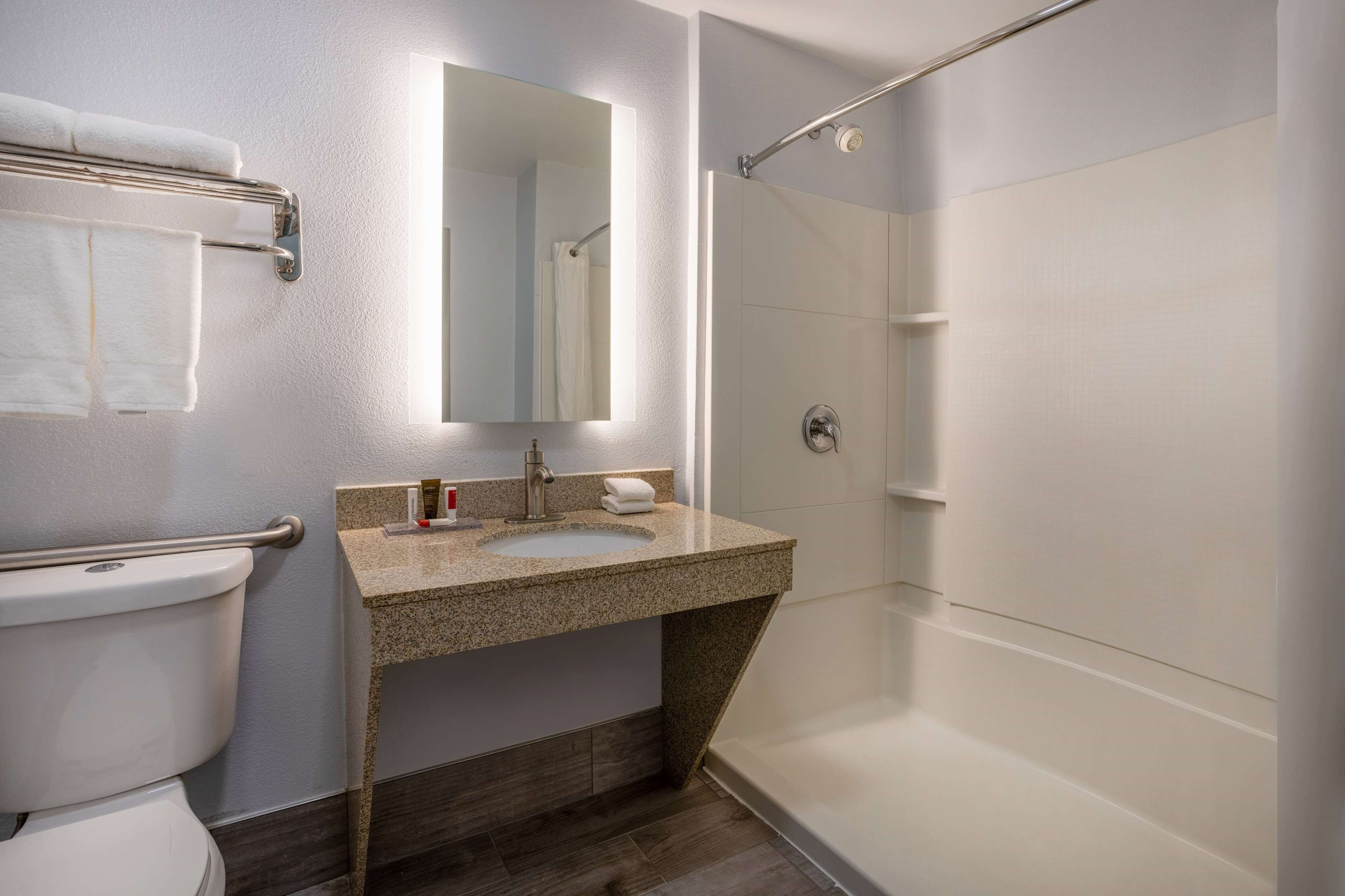 A modern bathroom with a toilet, sink, mirror, and shower.