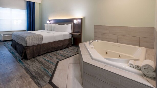 Une chambre d’hôtel avec un lit, une grande baignoire et une fenêtre avec des rideaux.