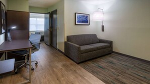 Une chambre d’hôtel équipée d’un bureau, d’une chaise, d’un canapé et d’une lampe fixée au mur.