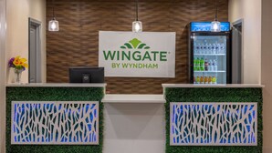 Un espace d’accueil avec une enseigne Wingate by Wyndham, un ordinateur Dell et un réfrigérateur pour boissons.