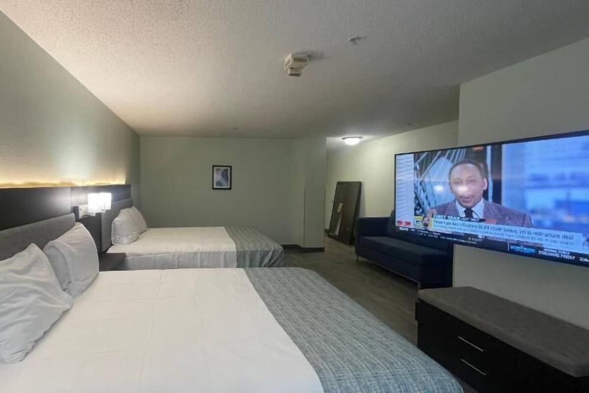 Une chambre d’hôtel avec deux lits, une télévision, un bureau et une chaise.
