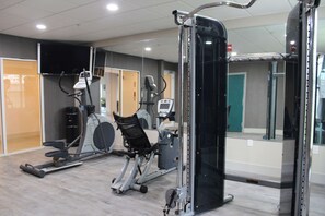 Une salle de sport équipée de divers appareils d’exercice, notamment des tapis de course et des appareils de musculation elliptique.