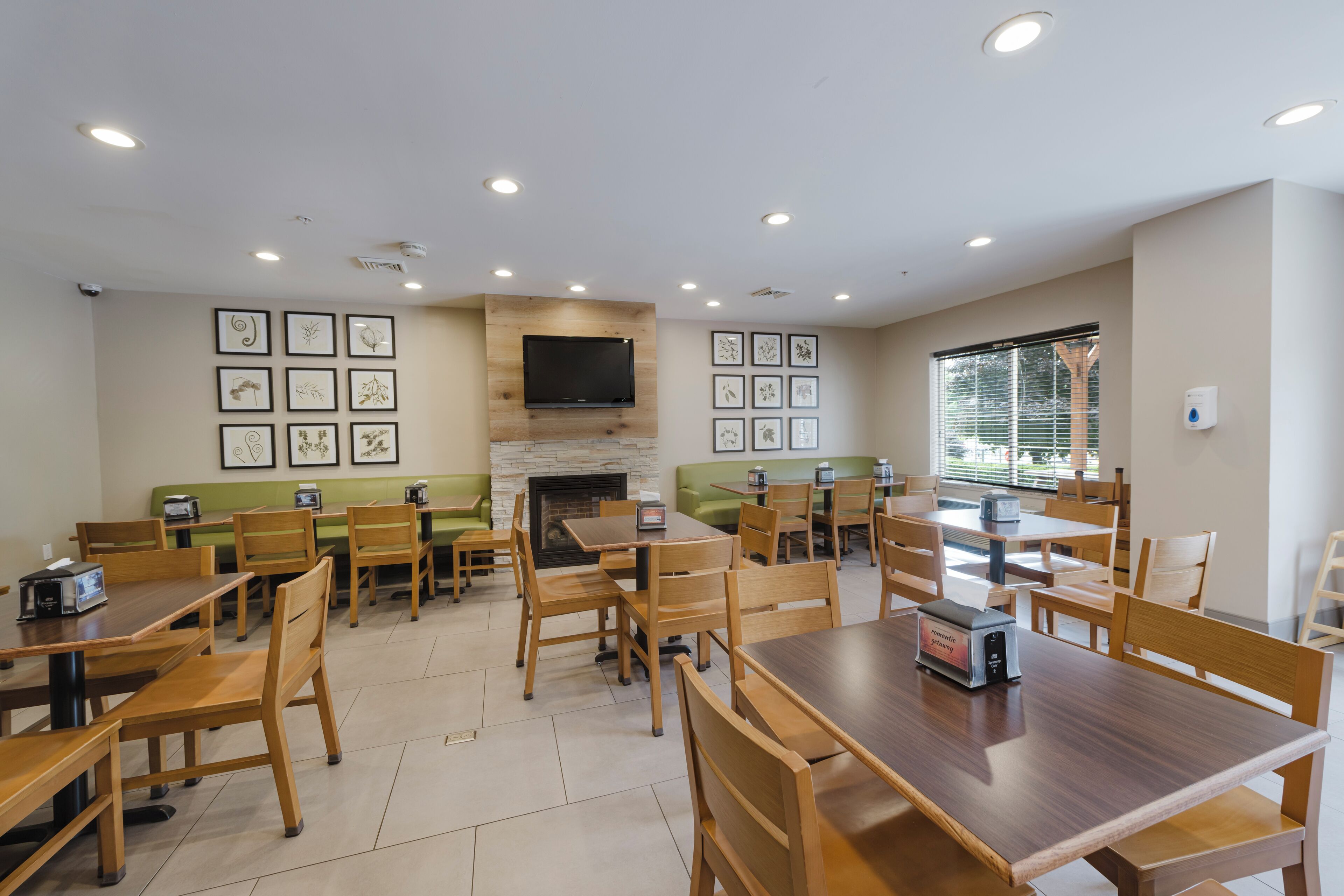 A dining area with wooden tables and chairs, a fireplace, and framed artwork on the walls.