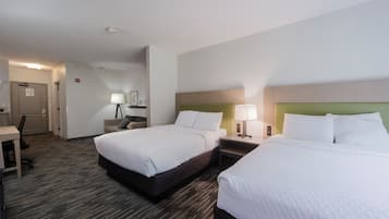 A hotel room with two beds, a desk, and a chair.