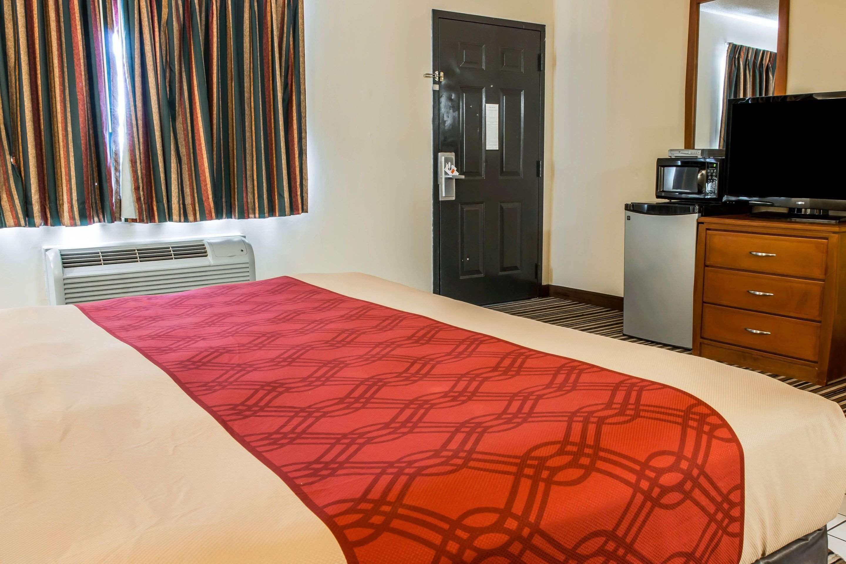 A hotel room with a bed, a television, a microwave, and a small refrigerator.