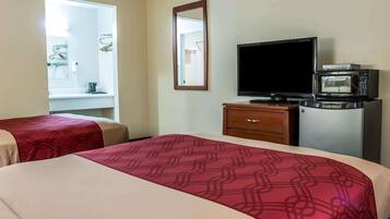 A hotel room with two beds, a TV, a microwave, and a small desk with a chair.