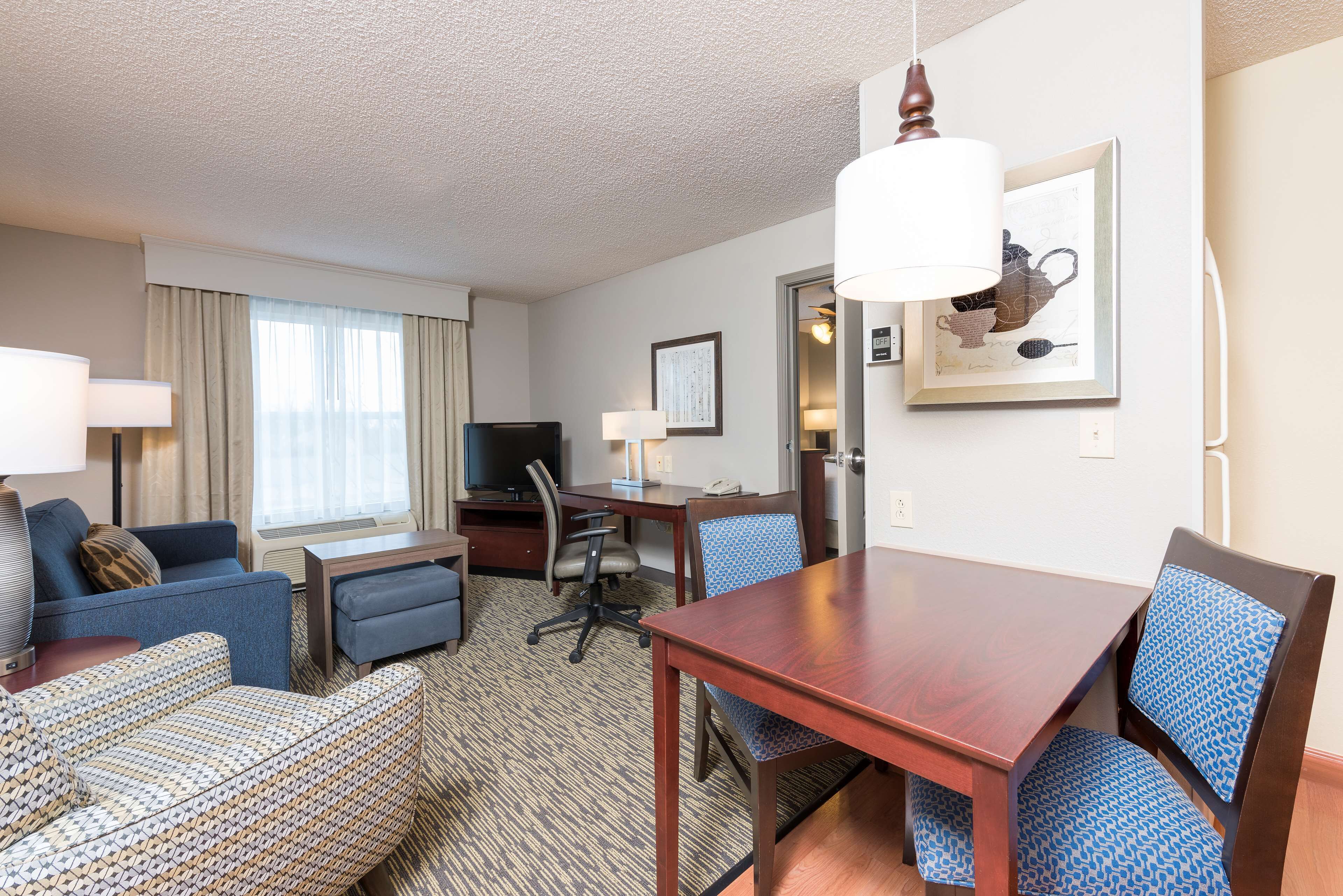 Une chambre d’hôtel comprenant un coin salon, une table à manger, un téléviseur et un bureau.
