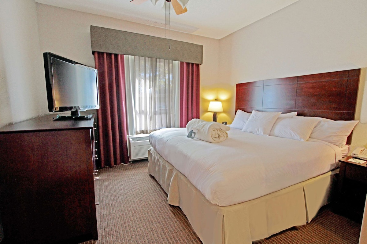 A hotel room with a bed, a TV, a lamp, and a desk.