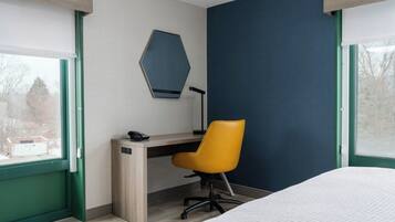 Un dormitorio con cama, escritorio, silla y ventana, y vistas al exterior.