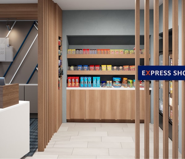 A hotel corridor with a wooden reception desk, a staircase, and a snack bar with various packaged goods.