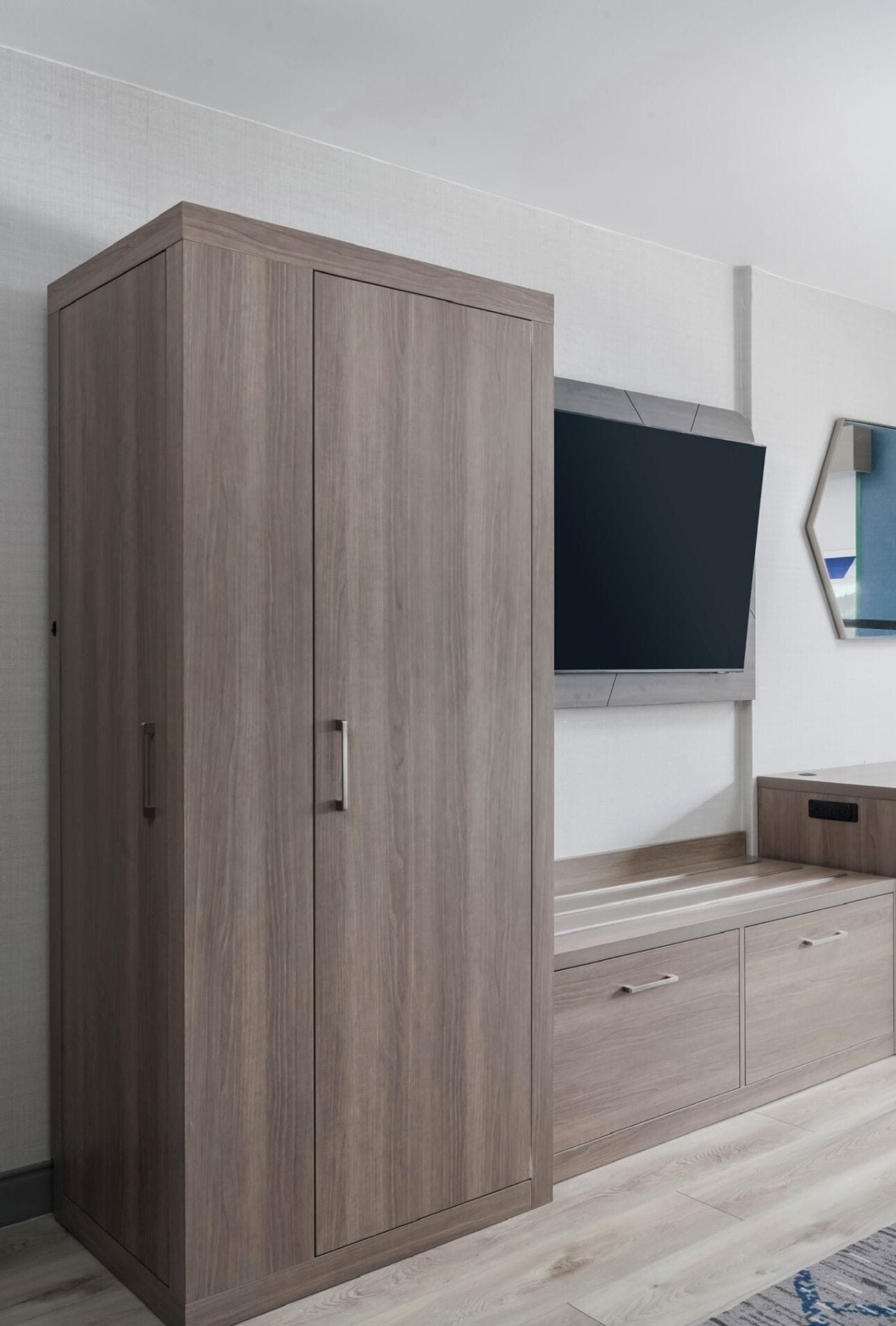 Una habitación con armario, televisor de pantalla plana montado en la pared y mueble bajo de madera.