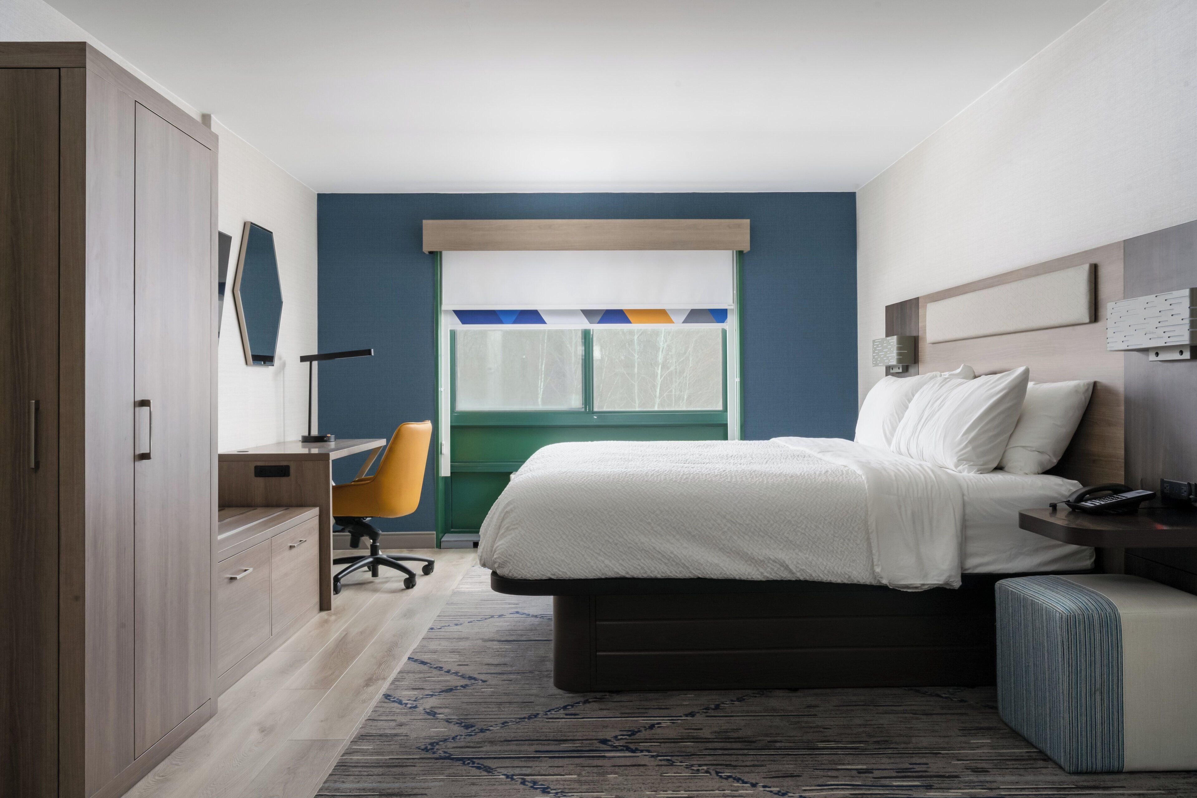 A bedroom with a bed, a desk, a chair, and a wardrobe.