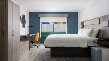 A bedroom with a bed, a desk, a chair, and a wardrobe.