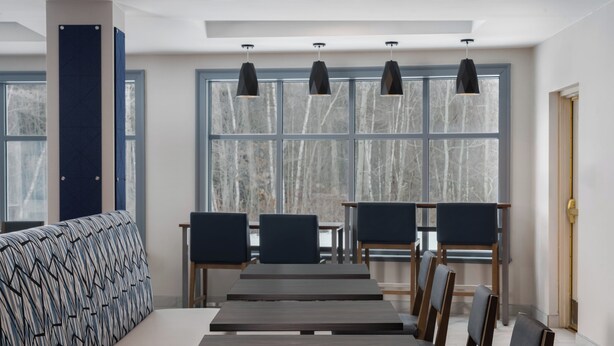 A modern dining area with a long table, multiple chairs, and pendant lighting. - Holiday Inn Express Hotel & Suites Drums by IHG (Drums)