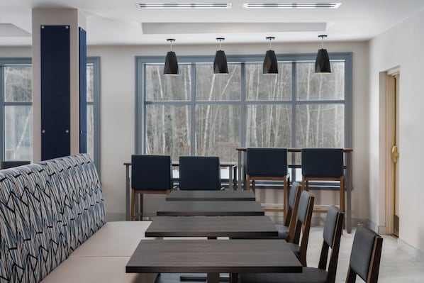 Un comedor moderno con una mesa larga, varias sillas e iluminación colgante.