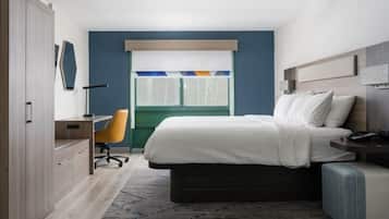 Une chambre à coucher comprenant un lit, une table de chevet, une chaise, un bureau, une armoire et une fenêtre avec des stores.